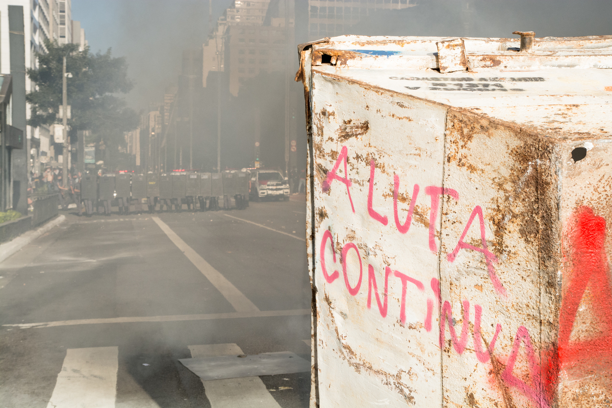 Manifestantes criam barridada com caçamba de entulho, para se proteger dos policiais 