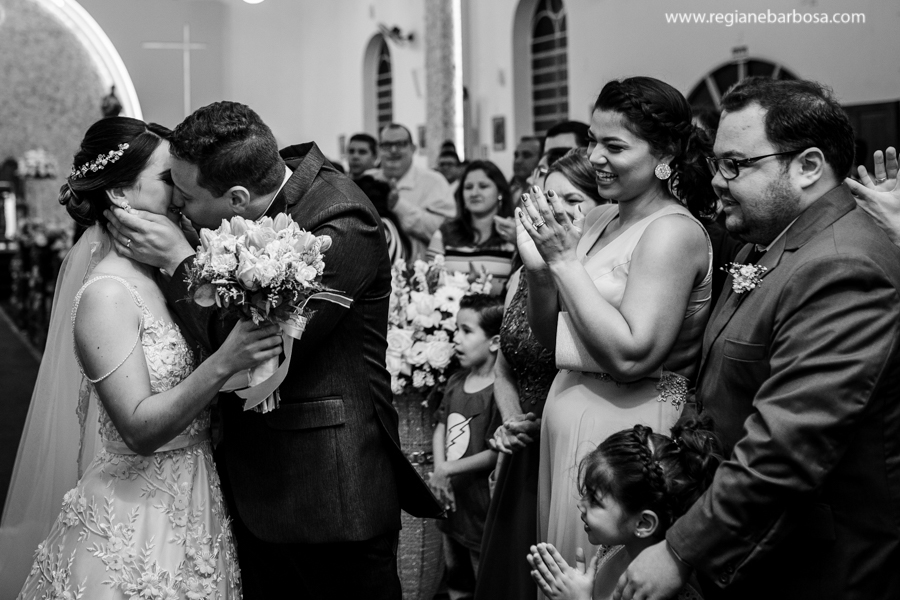 noivos se beijam e padrinhos vibram de alegria