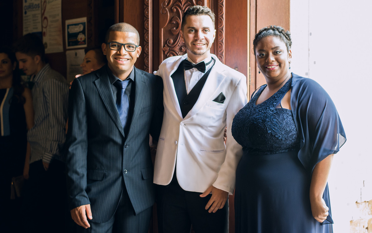 Noivo vestindo terno branco em frente a igreja São Sebastião, Louveira, SP