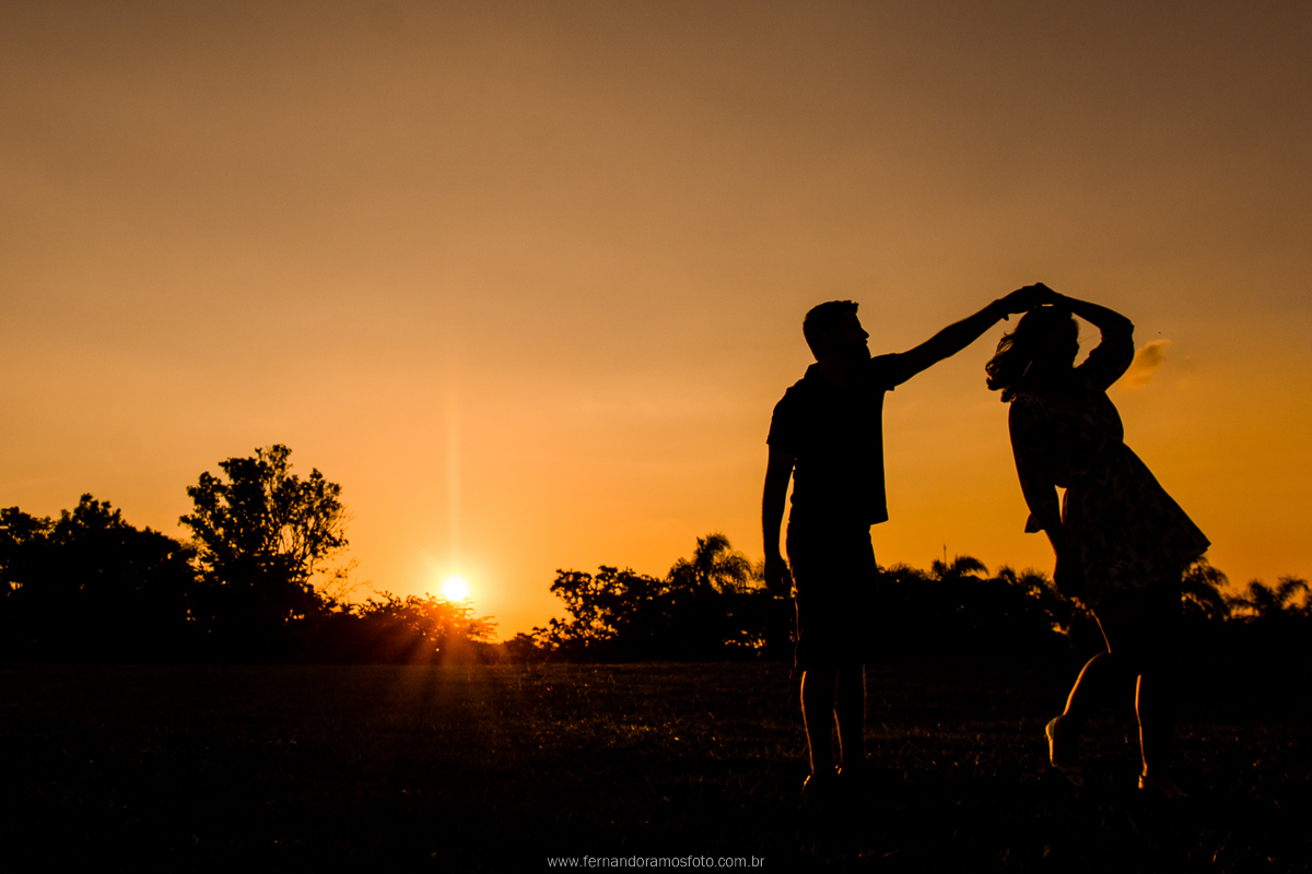 FOTOGRAFIA DE SILHUETA DO CASAL DANÇANDO DURANTE ENSAIO PRE-CASAMENTO AO POR DO SOL NO PARQUE ECOLOGICO DE CAMPINAS - SP