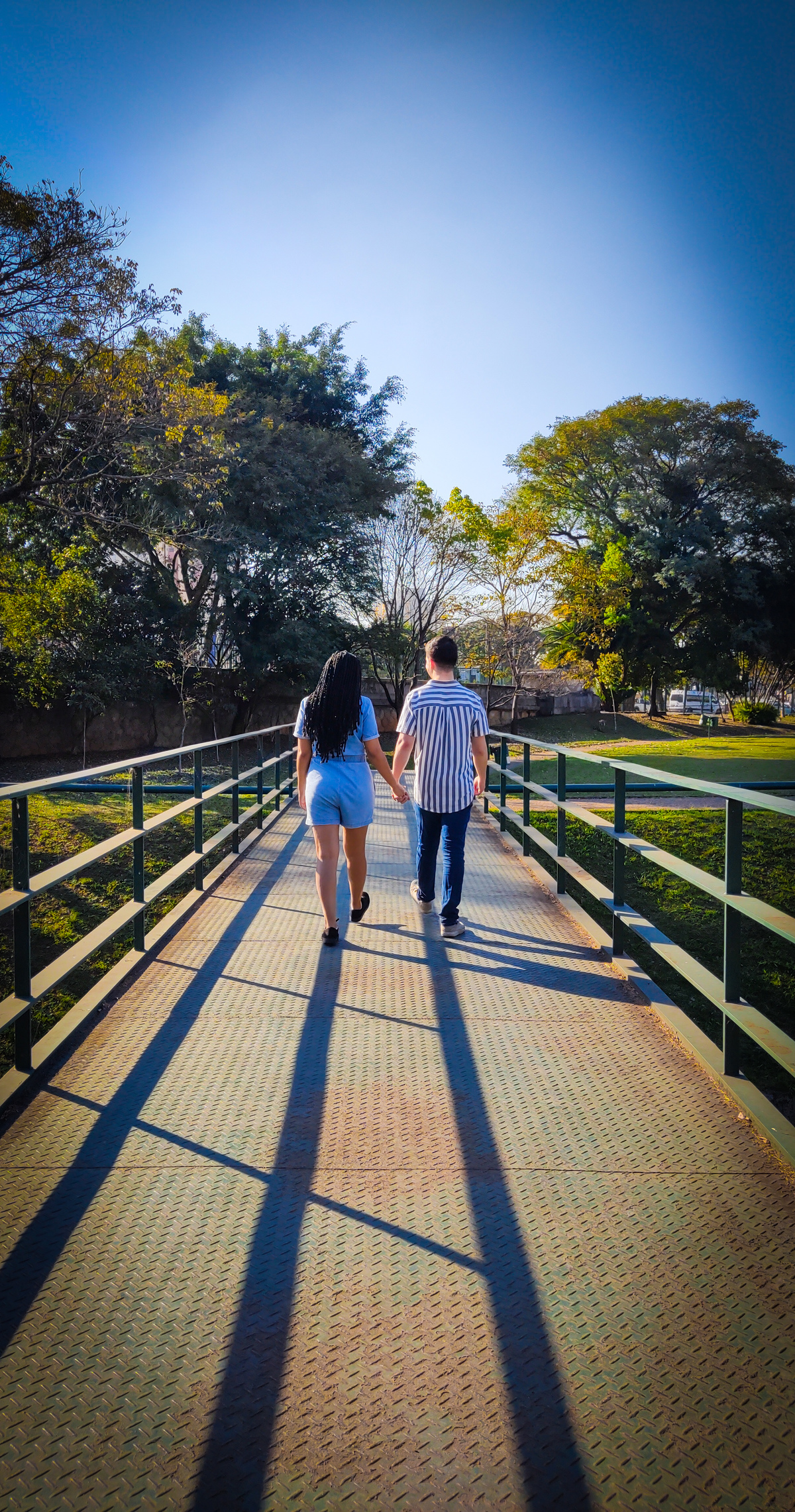 Casal de mãos dadas andando pela ponte