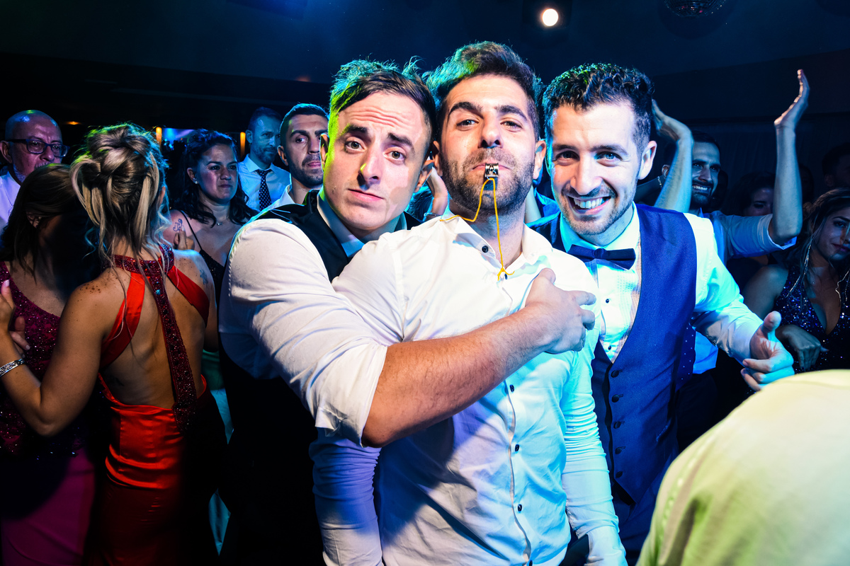 retrato divertido de hermano del novio con silbato en la boca, abrazo de un amigo y el novio que asoma. Liceo Naval, Nuñez, CABA.
