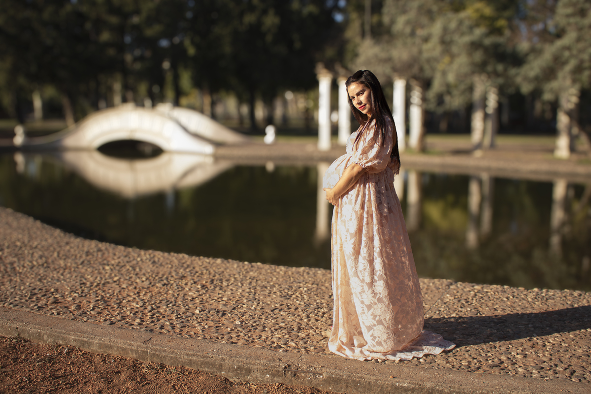 embarazada de perfil, delante de lago artificial y puente, vestido romántico