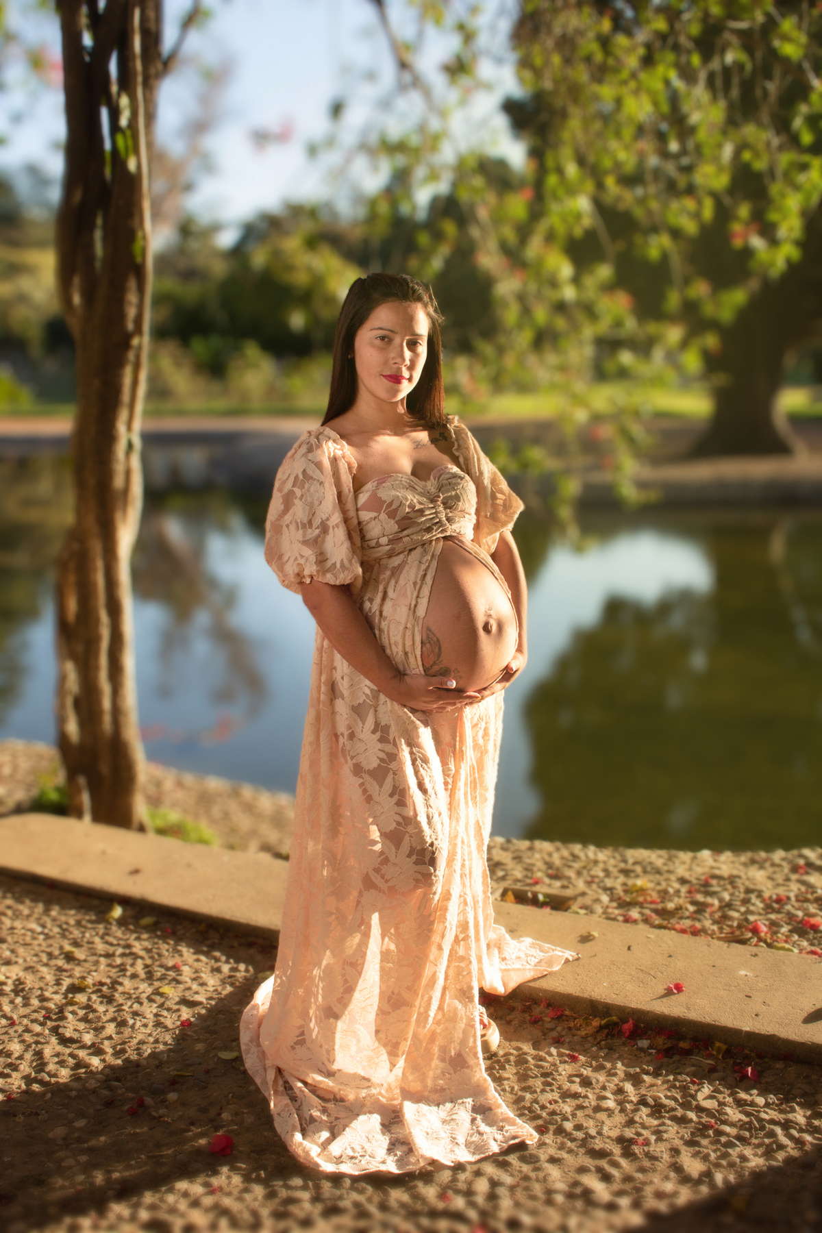 embarazada tres cuartos perfil, mirando su panza, plano general, delante de un árbol y lago, vestido romántico