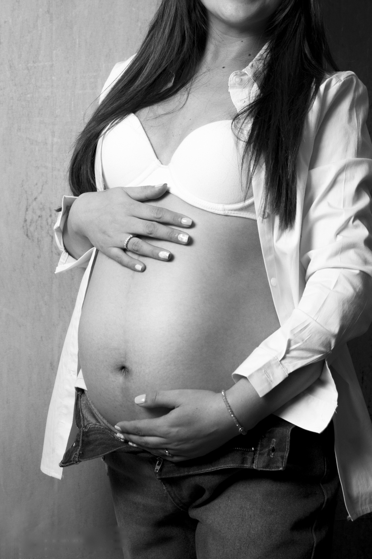 primer plano panza de embarazada con look informal en jean y camisa, en blanco y negro