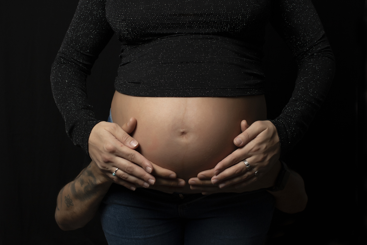 embarazada primerísimo plano con manos de pareja en la panza clave baja