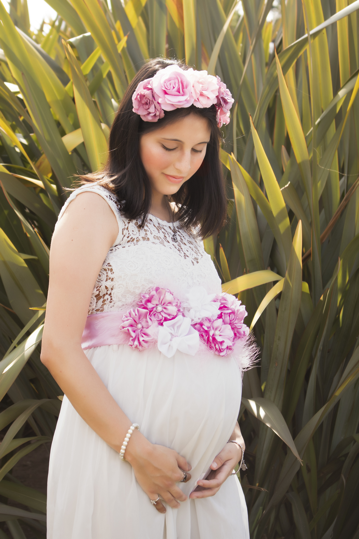 embarazada de perfil, vestuario estilo romántico con fondo de plantas 