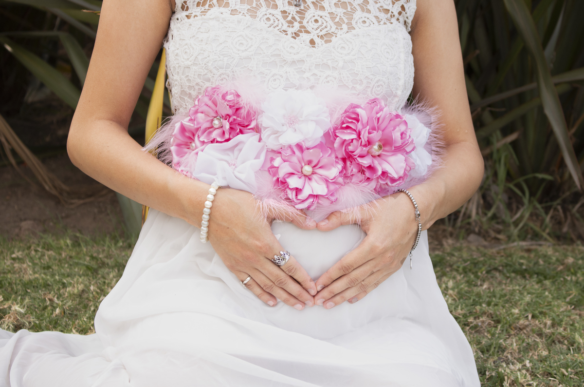 embarazada sentada de frente vestuario estilo romántico con fondo de plantas 