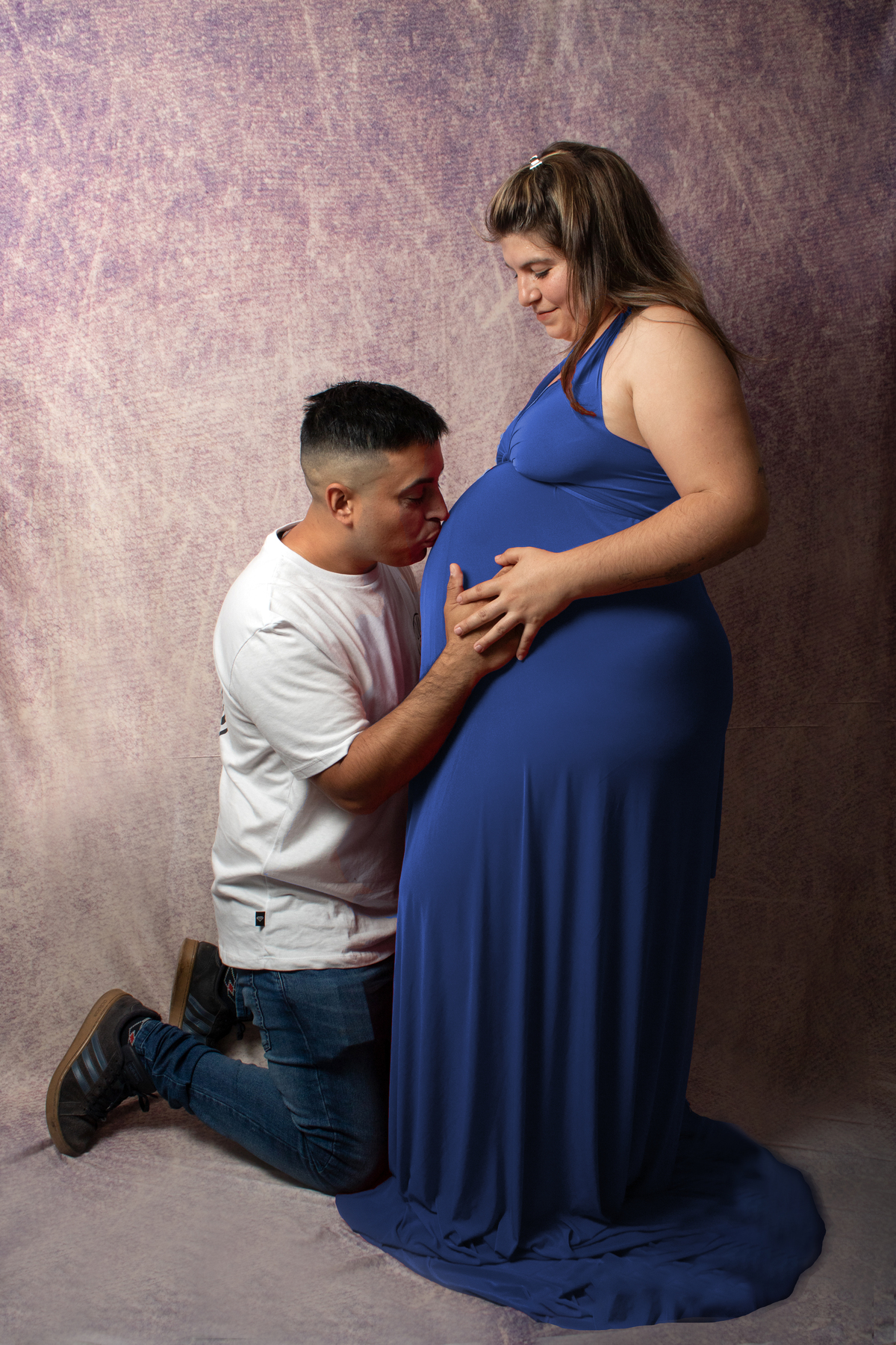embarazada y su pareja dandole un beso a la panza