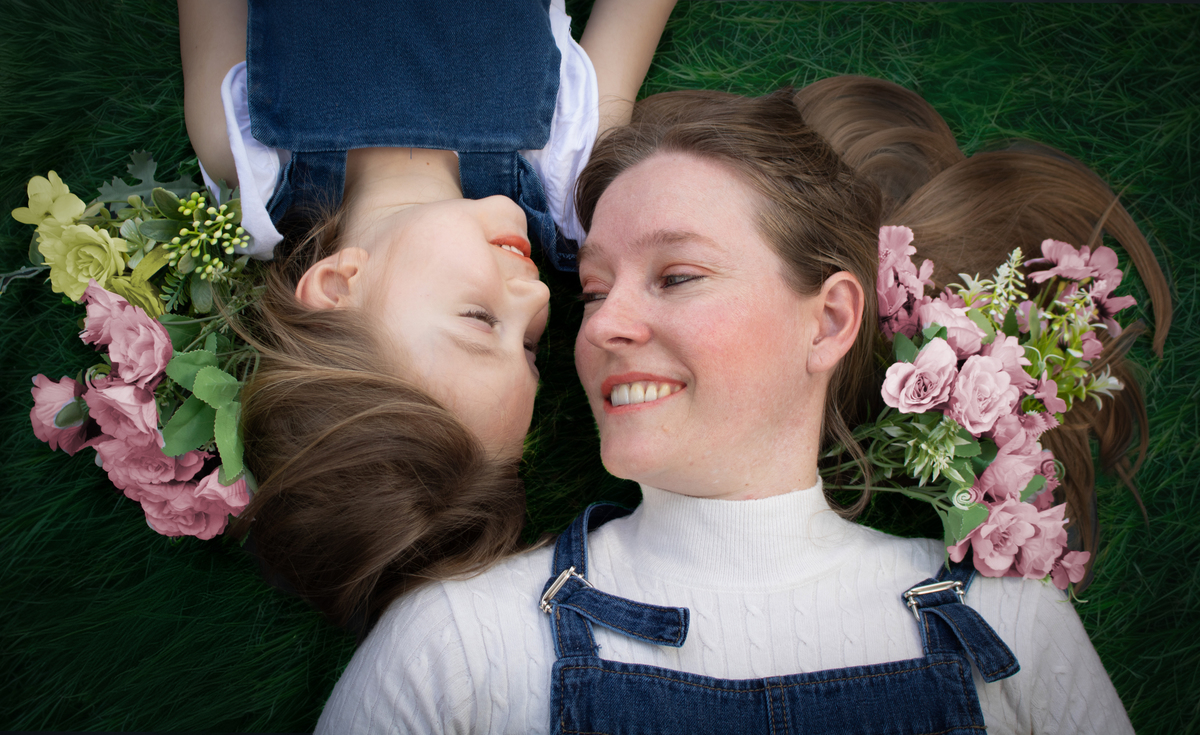 Madre e hija acostadas sobre el césped mirándose, primer plano