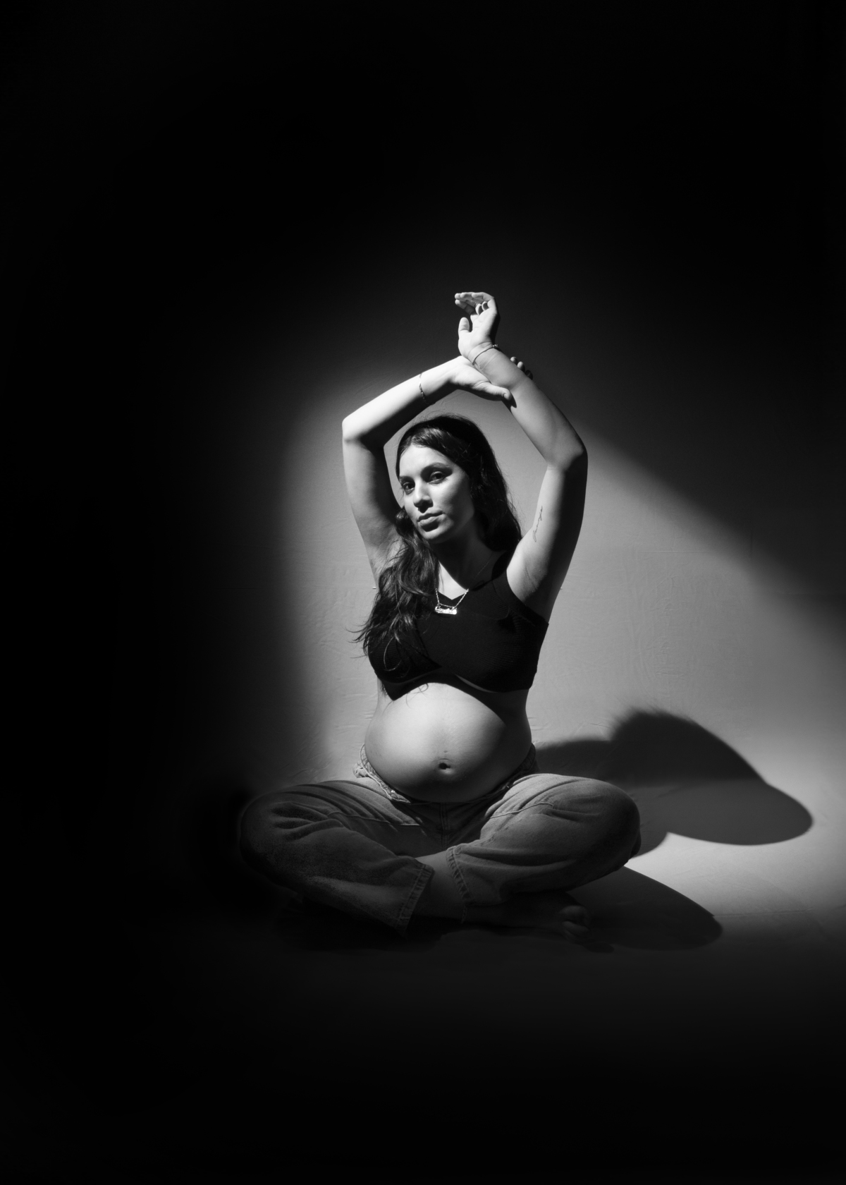 embarazada con ropa informal sentada sobre el piso , fotografía en blanco y negro