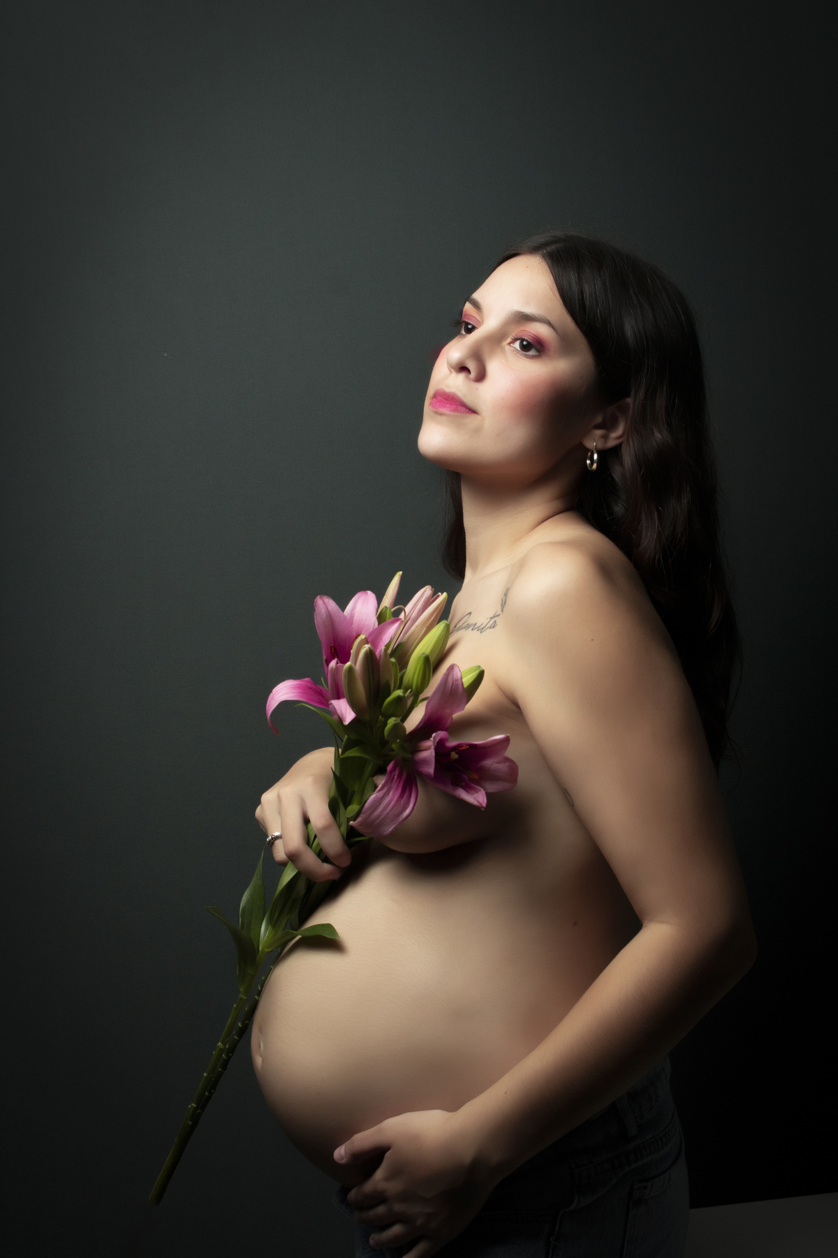 embarazada con el torso desnudo cubriéndose con flores de lilium 