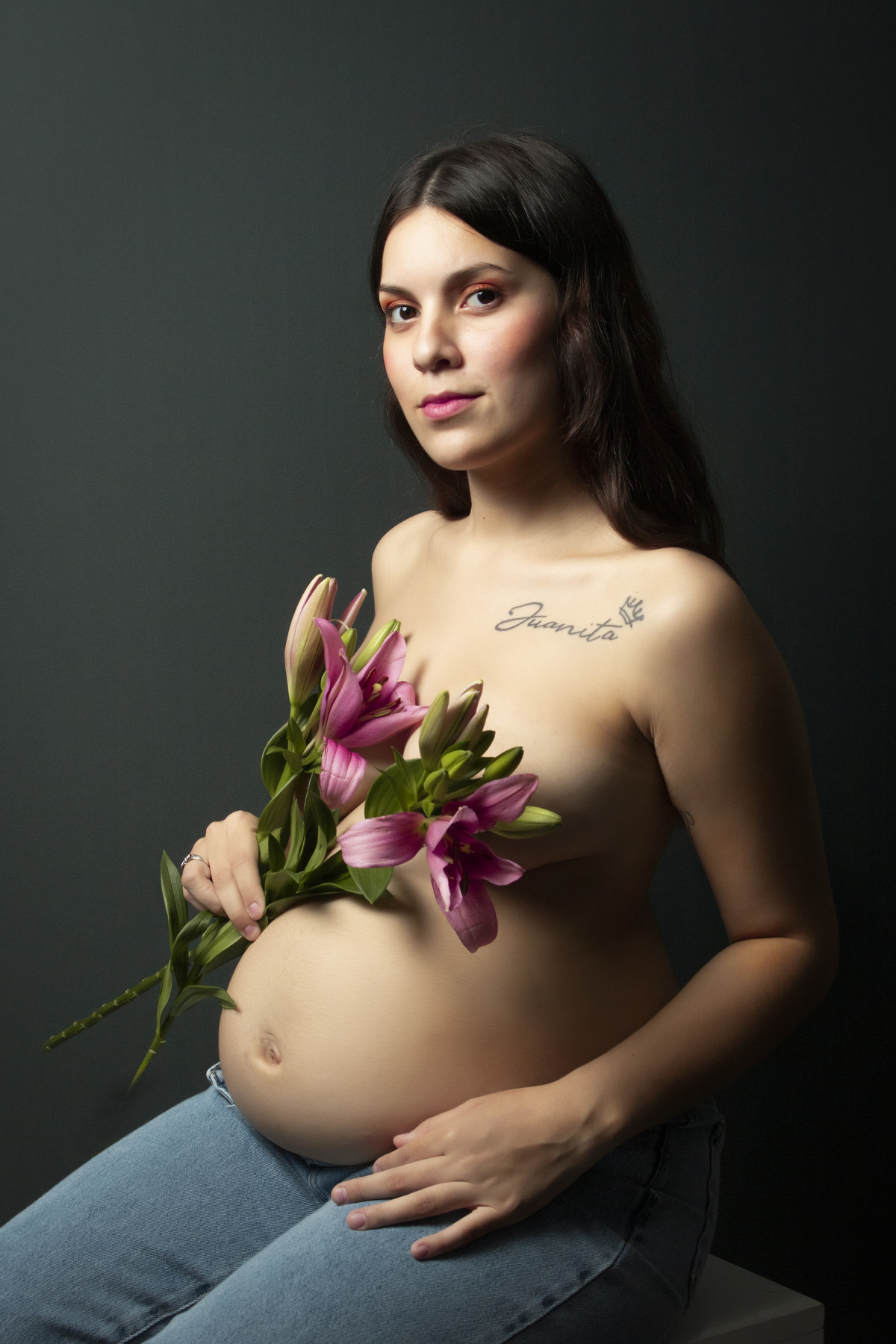 embarazada con el torso desnudo cubriéndose con flores de lilium