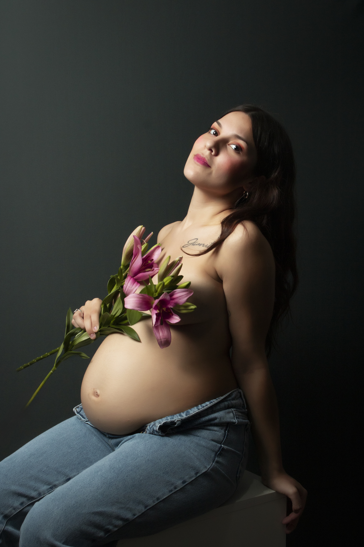 embarazada con el torso desnudo cubriéndose con flores de lilium
