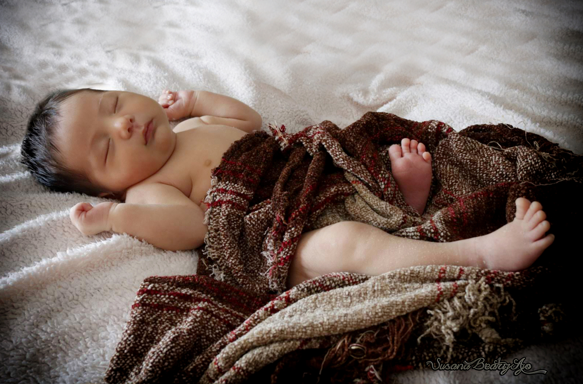 bebe  acostado entero con manta hilo marrón tres cuarto perfil