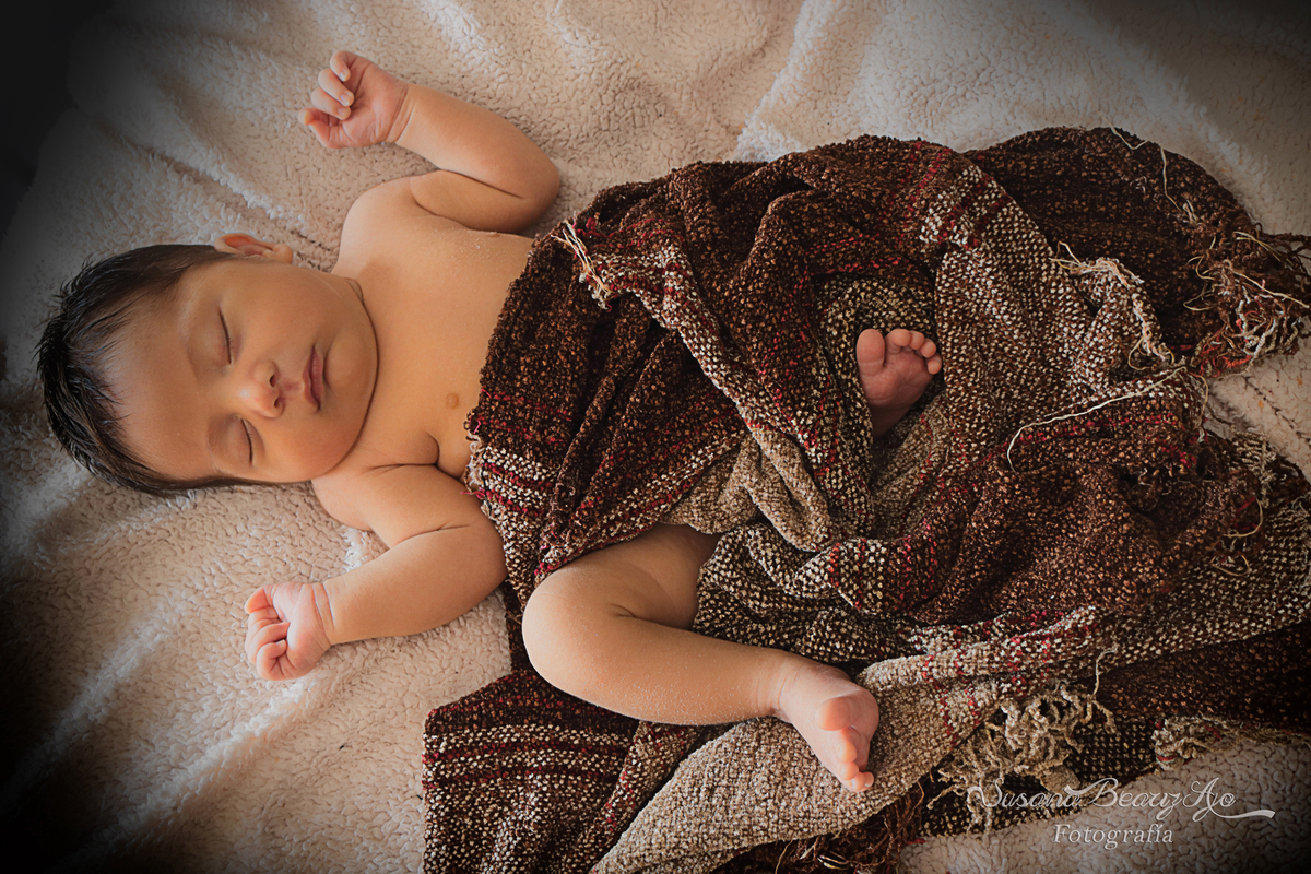 bebe  acostado entero con manta hilo marrón visto de arriba