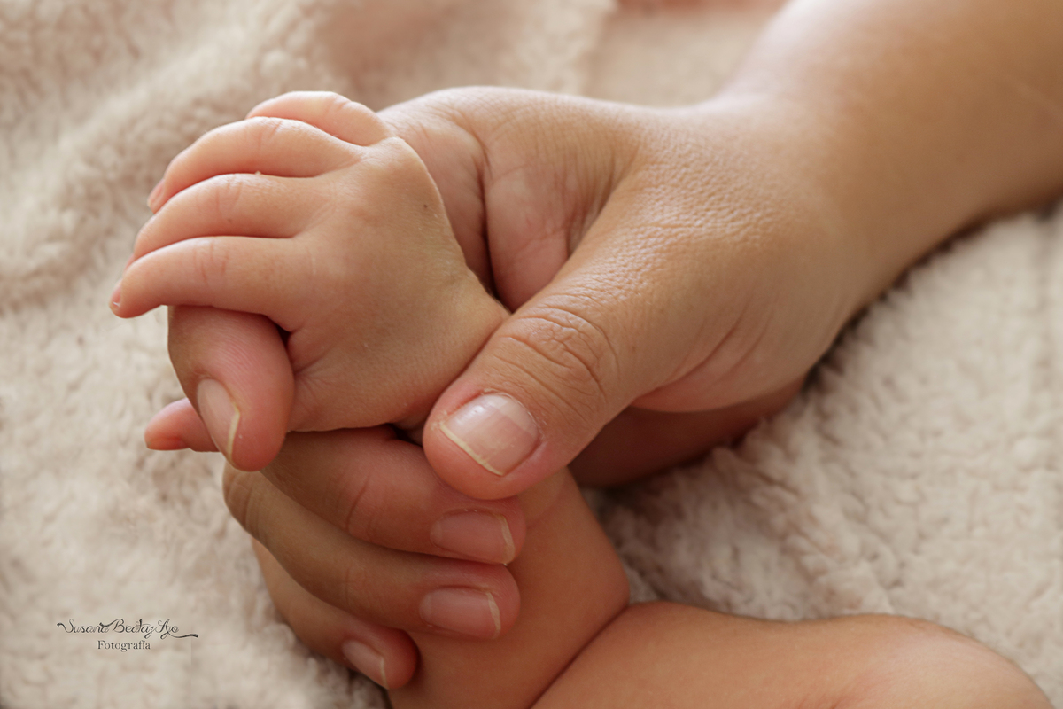 manito de bebe con mano de mamá, sobre fondo blanco