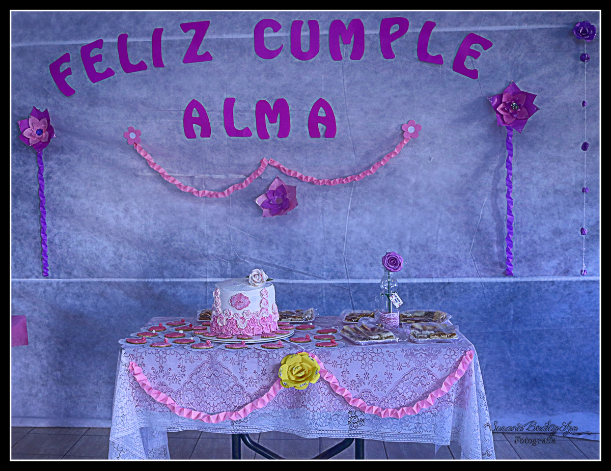 mesa con torta de cumpleaños blanca decorada con rosas rosas
