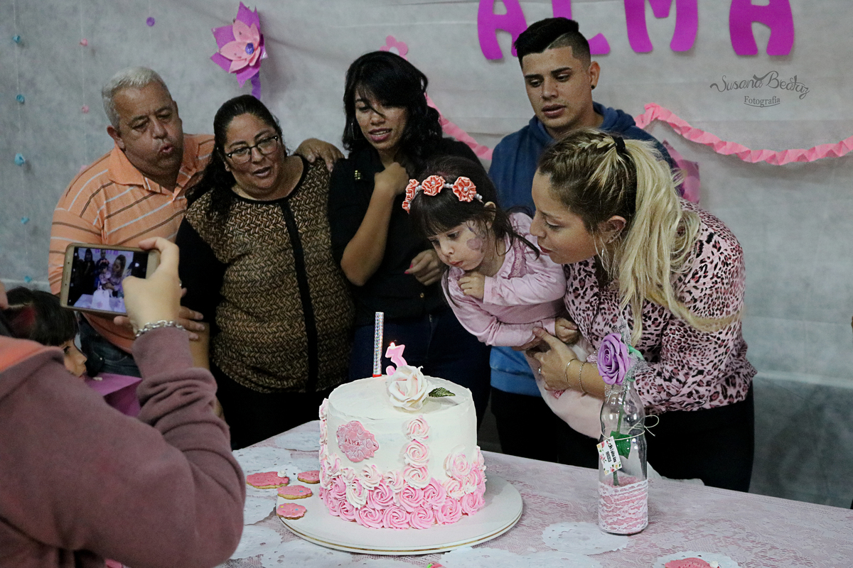 familia soplando las velitas de la torta de cumpleaños infantil