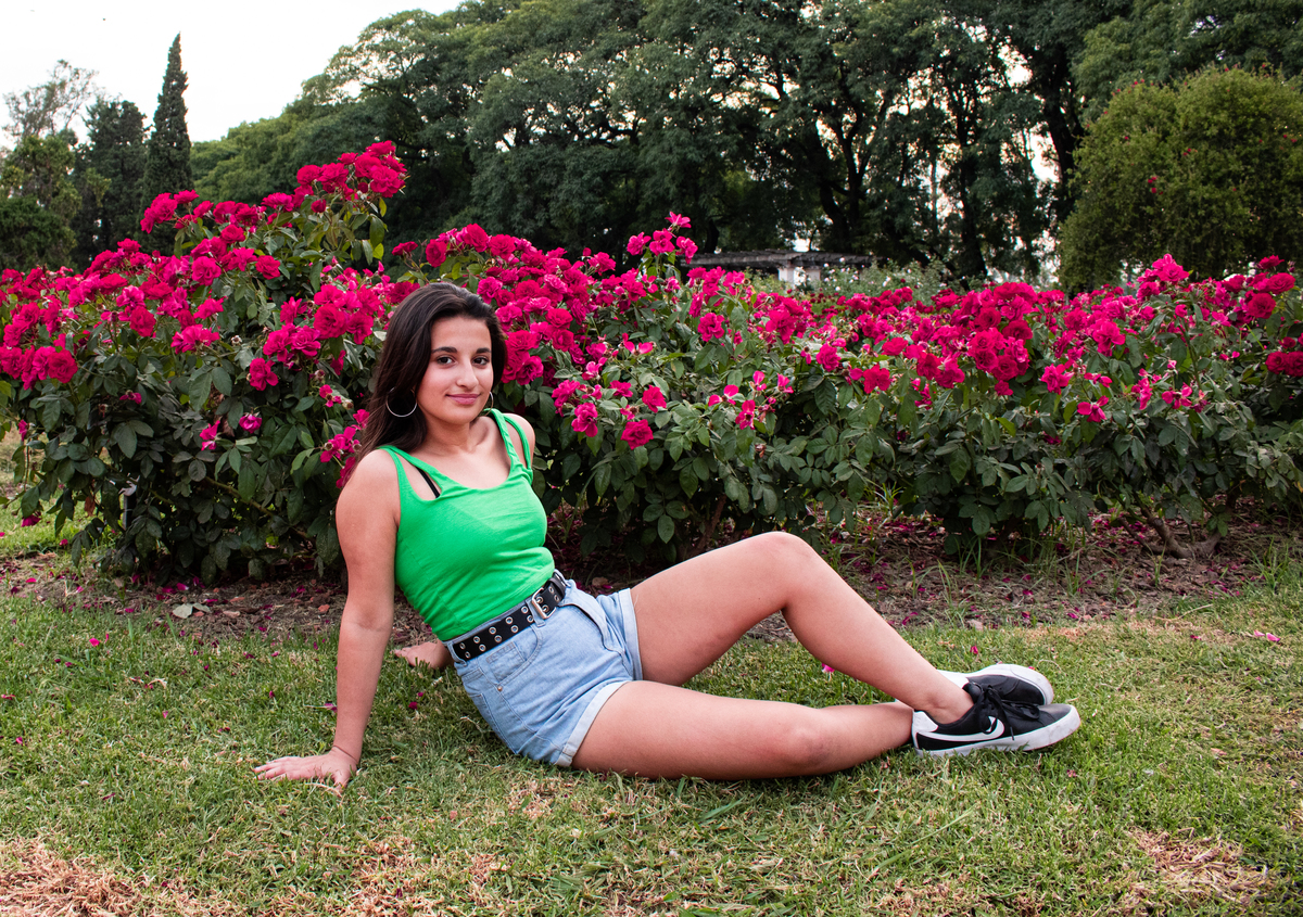 quinceañera sentada delante del rosedal