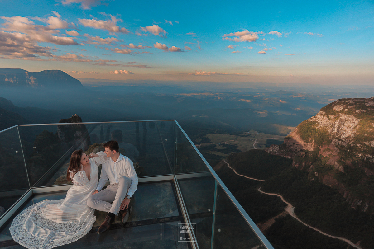 casal sentado no mirante de vidro com a serra do corvo branco ao fundo