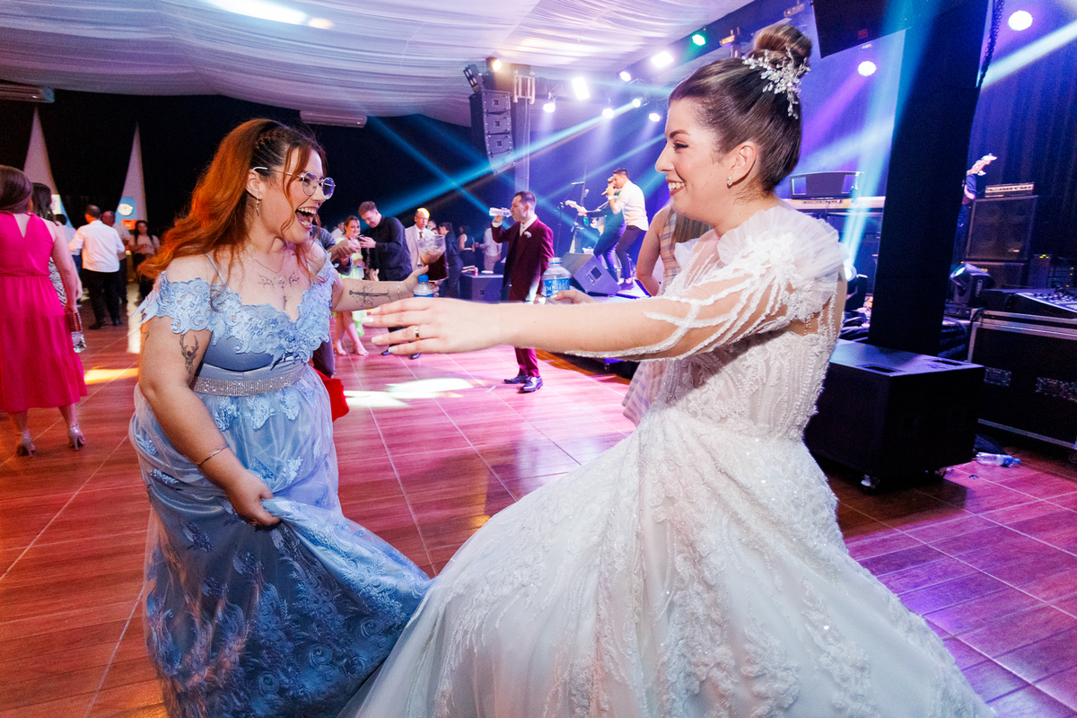 noiva e madrinha aproveitando a pista de dança com energia. Fotografias que mostram a conexão entre os convidados e a noiva durante a festa.