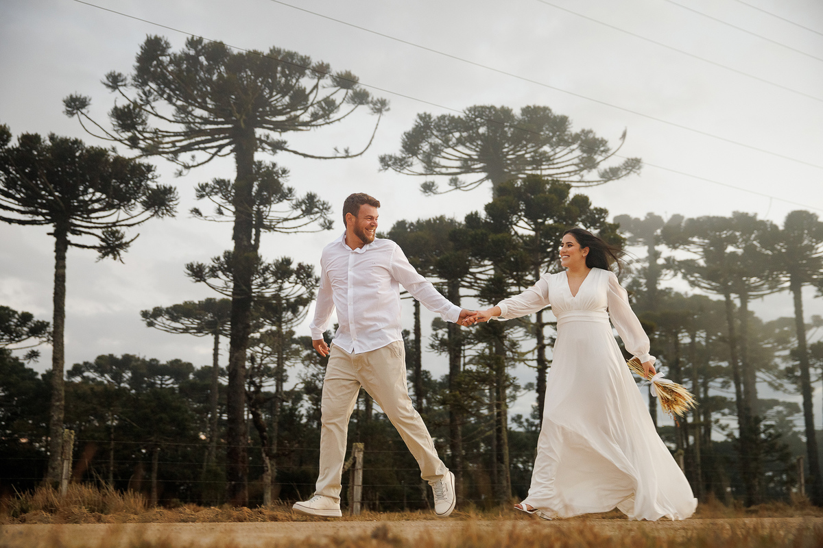 Casal caminhando entre árvores de araucária.
Ensaio pré-wedding descontraído com clima típico da serra catarinense.