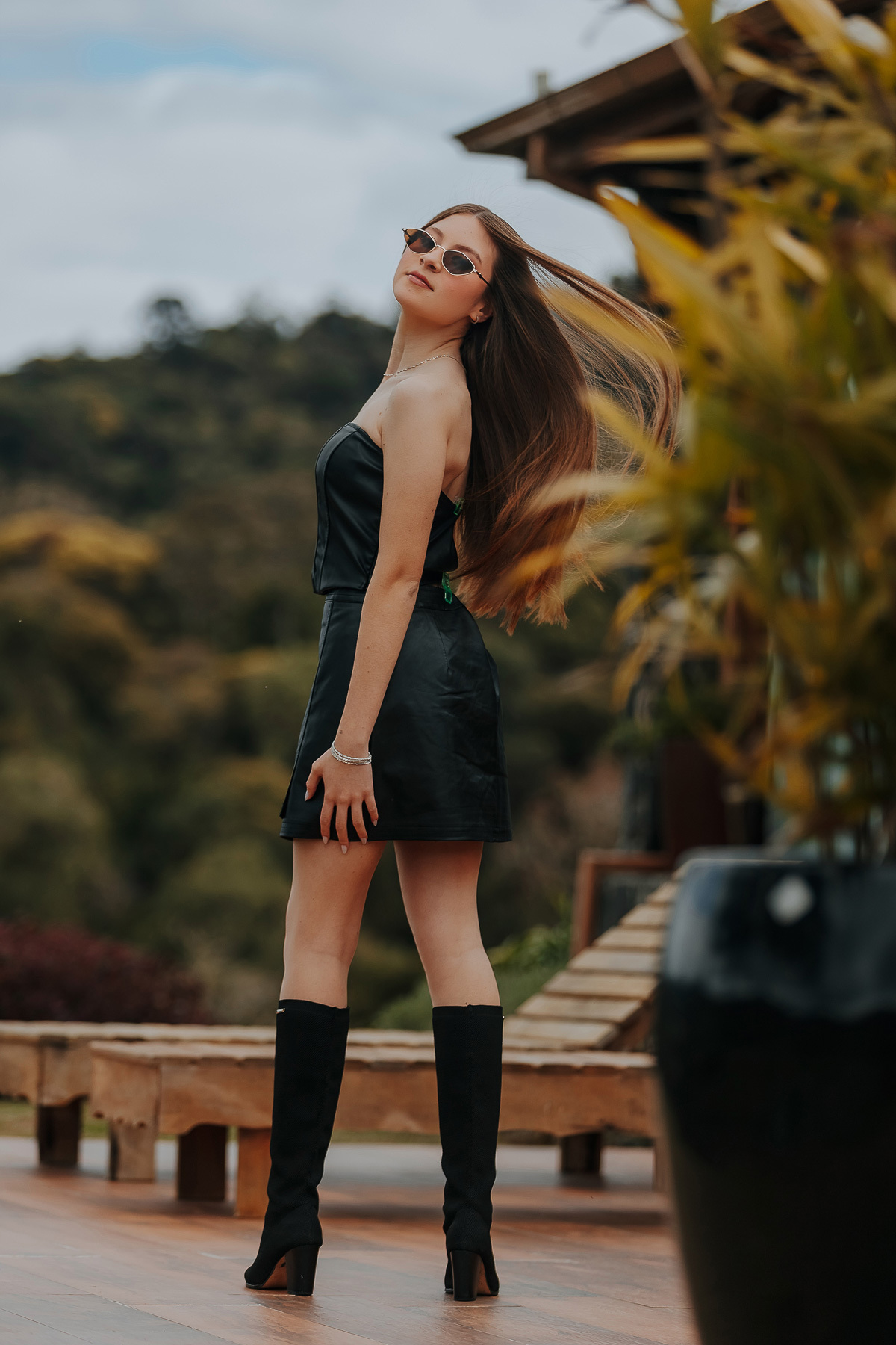 Laís caminha entre o campo com um sorriso suave, o vestido fluindo ao vento. Uma imagem que simboliza os sonhos e a liberdade dos 15 anos.