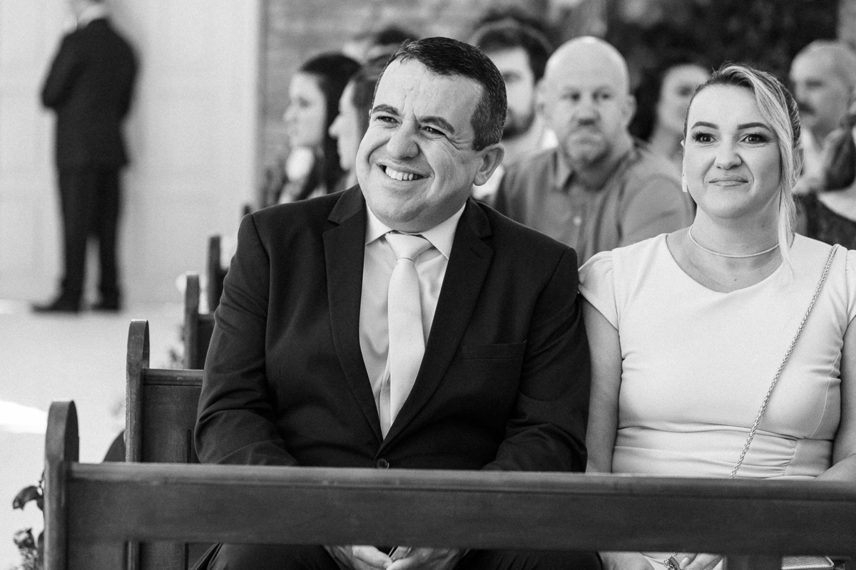 Noivos sorrindo durante a cerimônia de casamento emocionante na Igreja da Taipa.