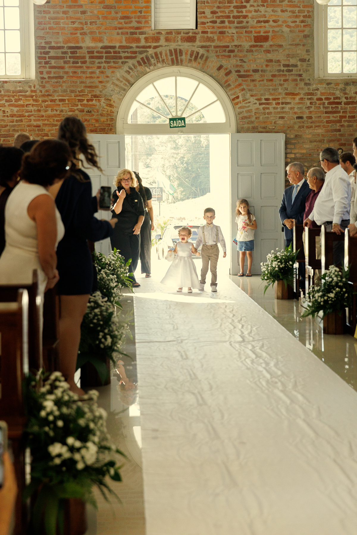 Entrada da noiva na cerimônia de casamento diante dos convidados.