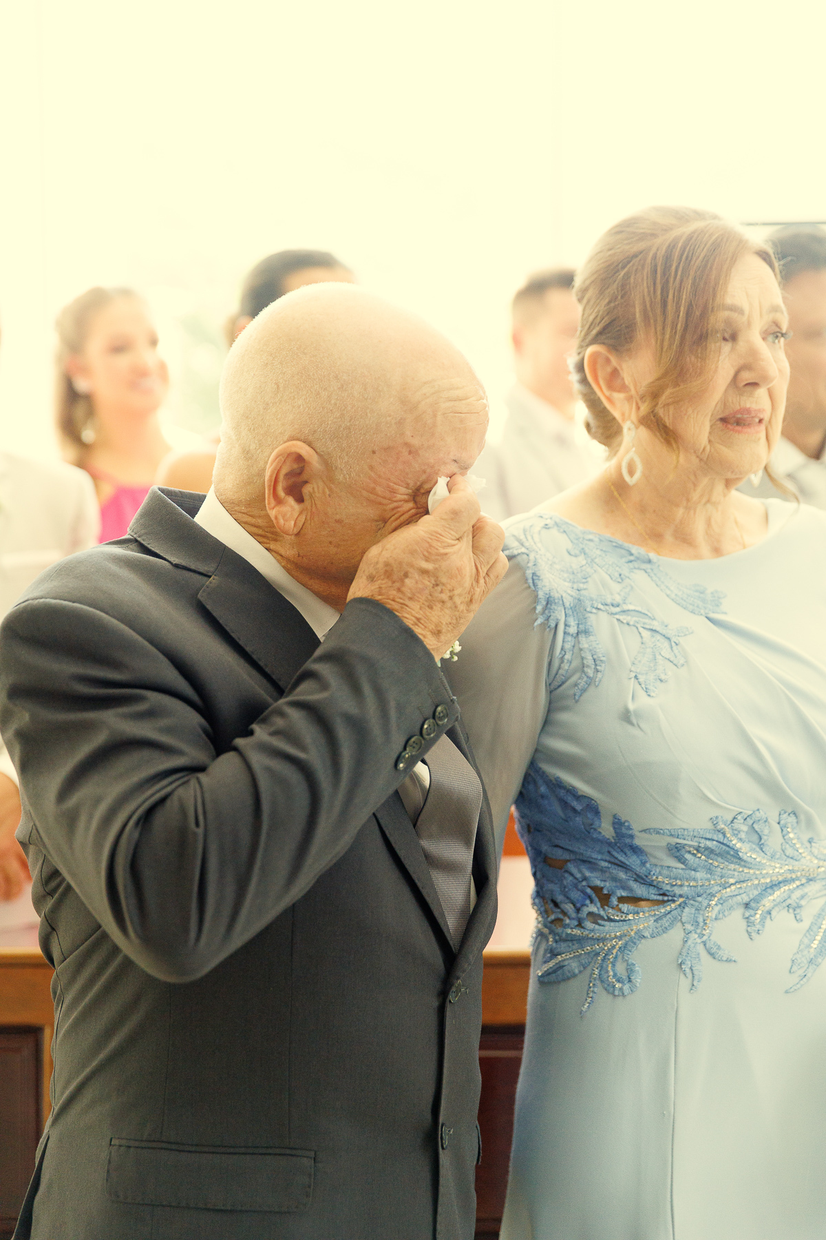 Pai emocionado enxugando as lágrimas durante o casamento da filha.