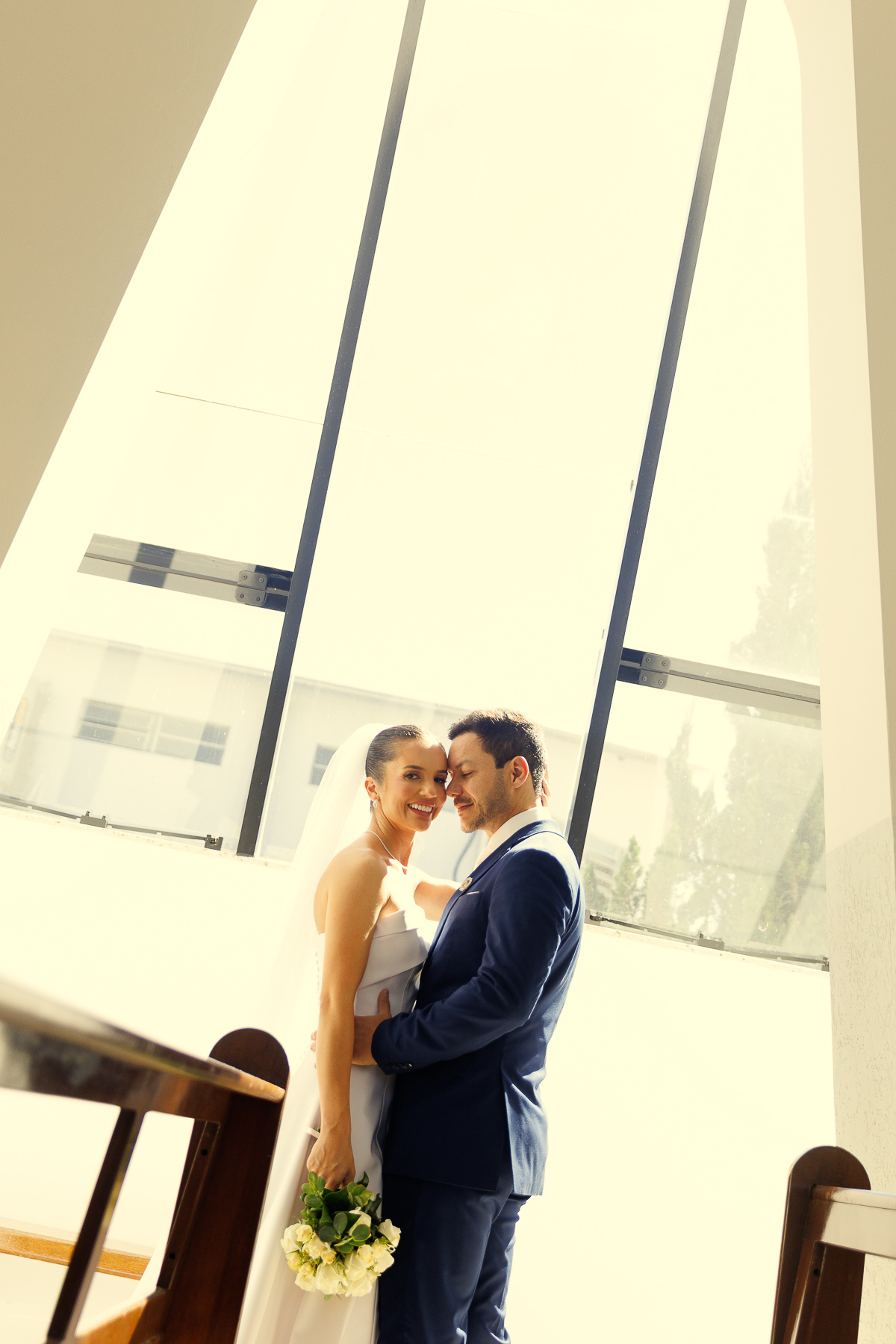 Casal em momento romântico iluminado pela luz natural após o casamento.