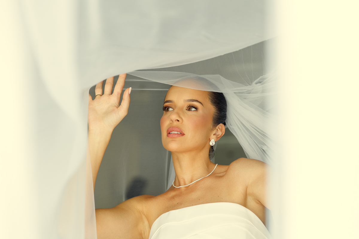 Noiva segurando o véu durante retrato elegante após a cerimônia.