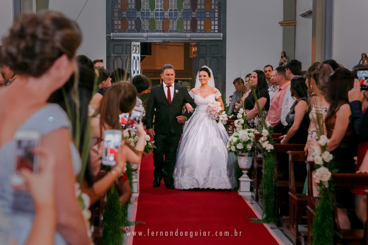 noiva entrando na igreja ao lado do seu pai durante a cerimonia de casamento 