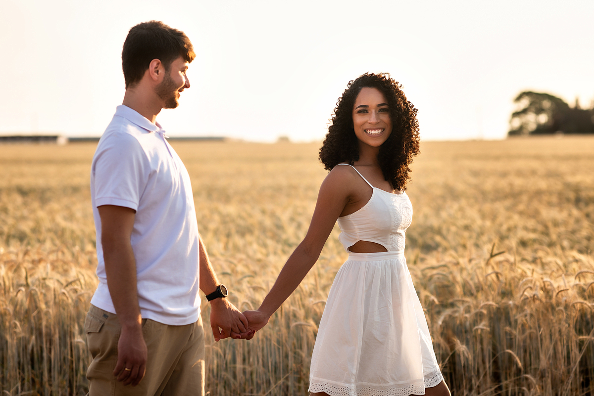 casal caminhando em campo de trigo com o por do sol ao fundo em Holambra