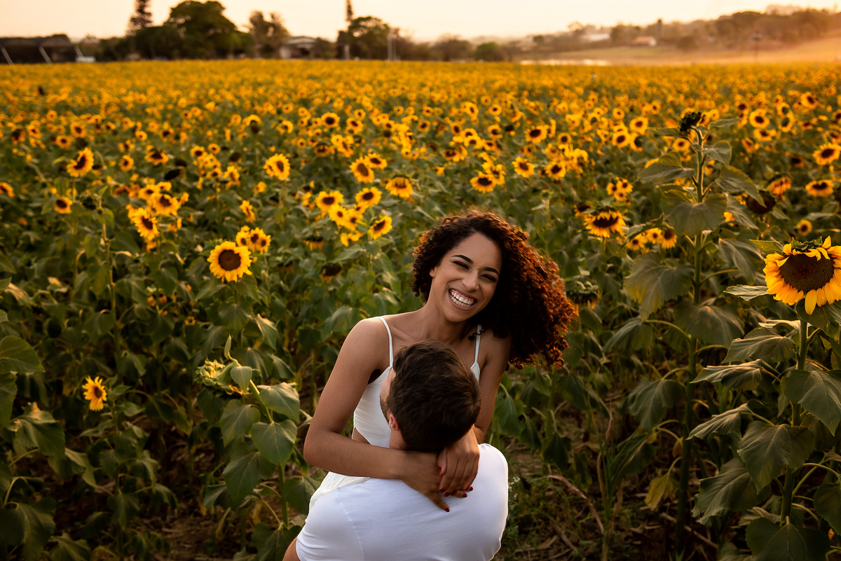 casal abraçado em campo de girassol com o por do sol ao fundo em Holambra