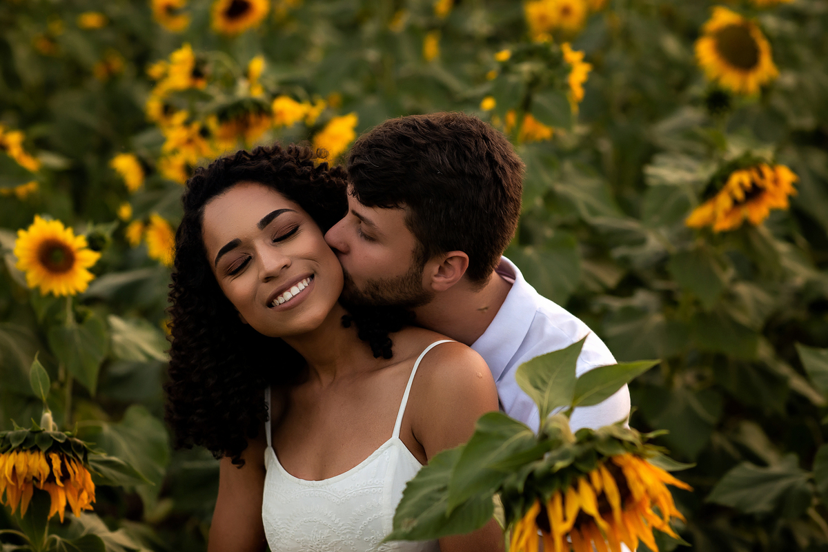 casal abraçado em campo de girassol com o por do sol ao fundo em Holambra