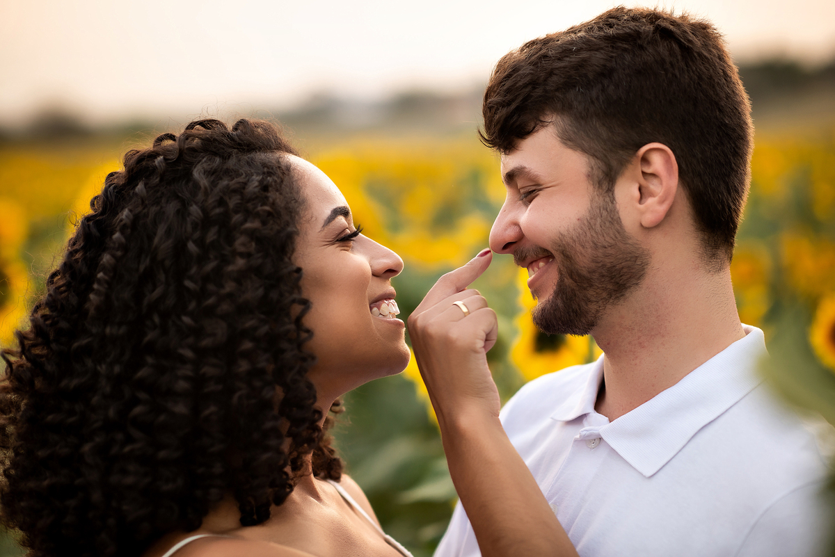 casal abraçado em campo de girassol com o por do sol ao fundo em Holambra