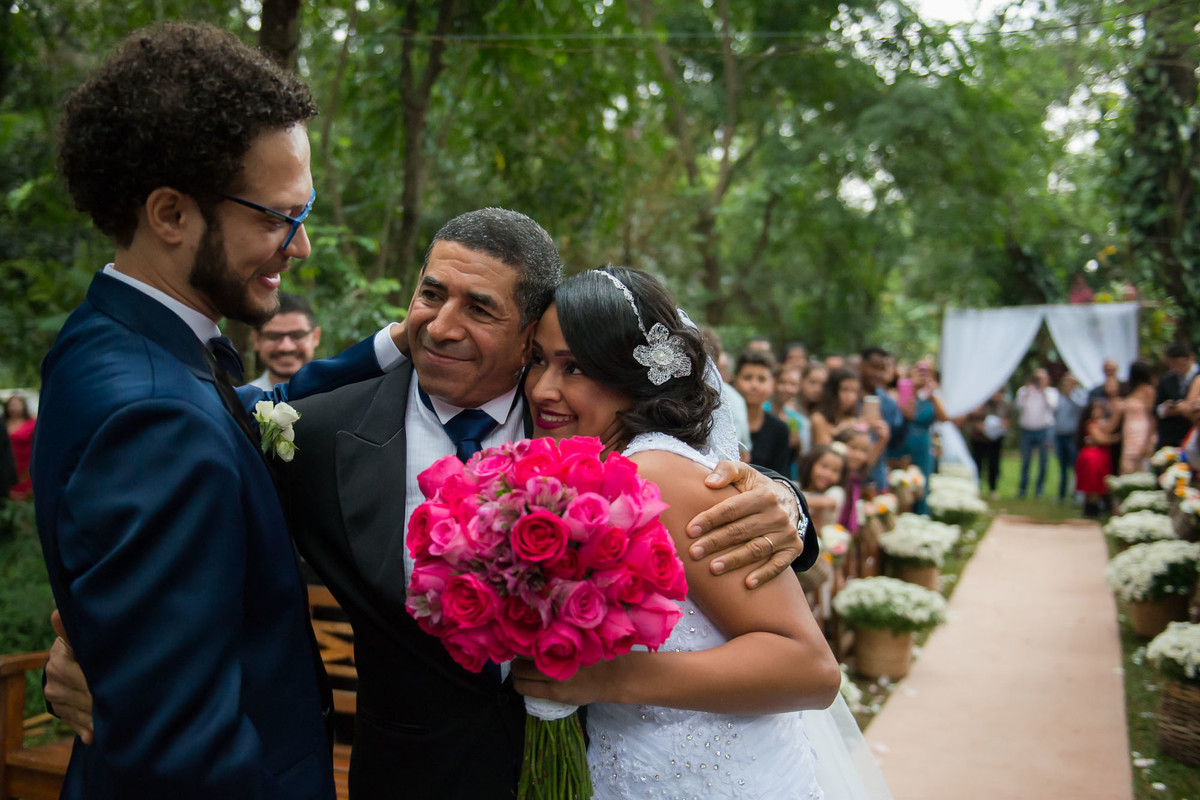 pai entrega a noiva ao noivo com um abraço caloroso