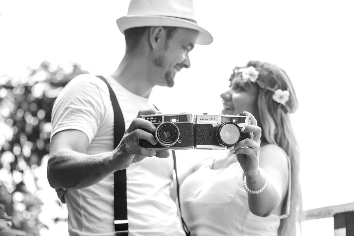 casal com camera fotografica na mão na praia do iporanga no guaruja