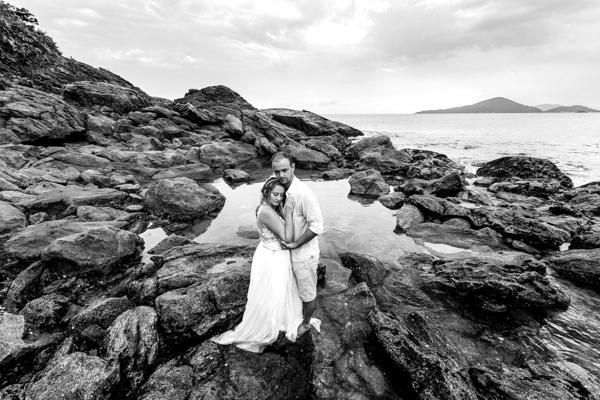 casal abraçados nas pedras na praia do sao pedro no guaruja