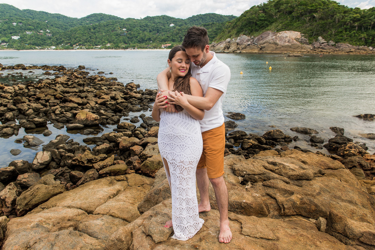 casal abraçados em cima da pedra com mar ao fundo