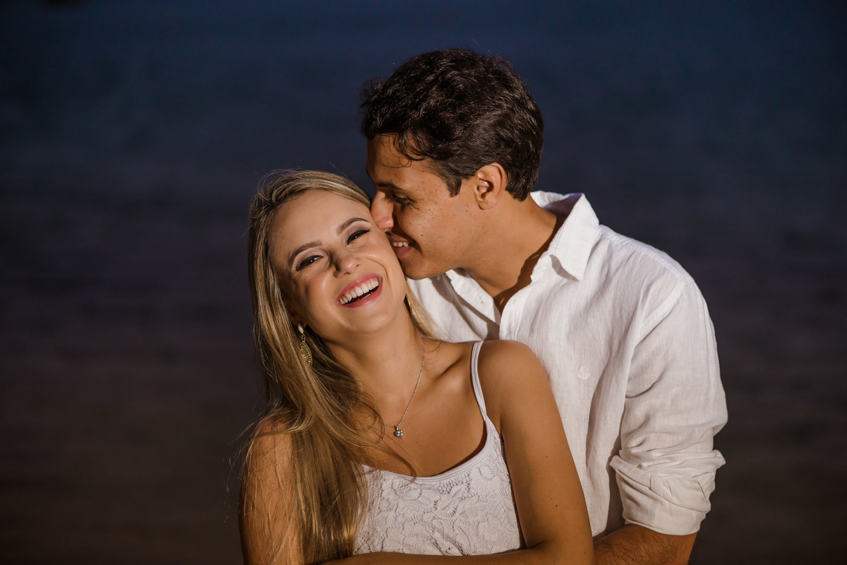 noivo beijando com mar de fundo