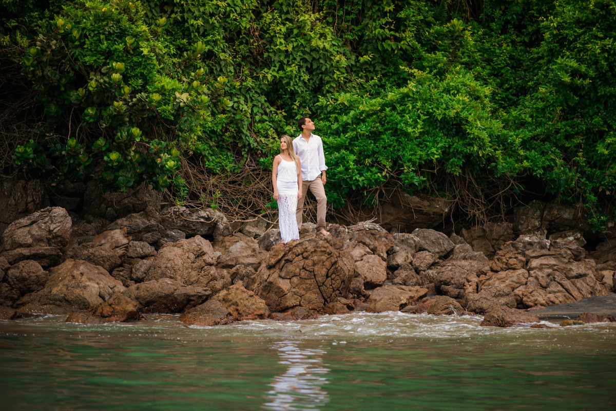 casal em rocha com o mar