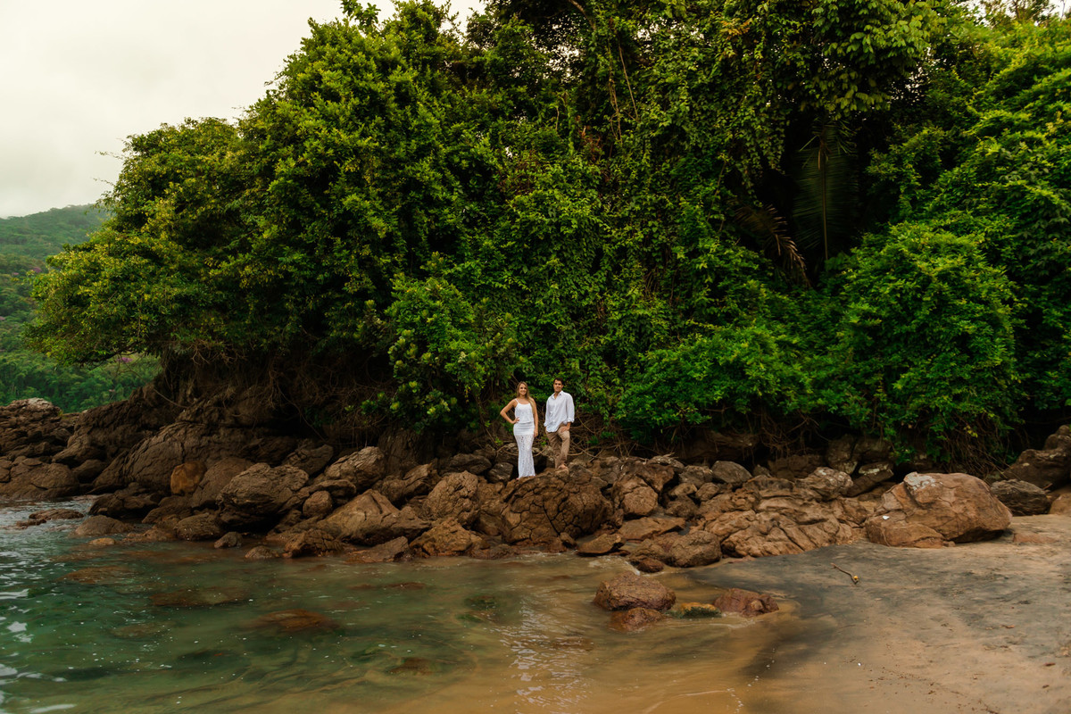 casal em rocha com o mar
