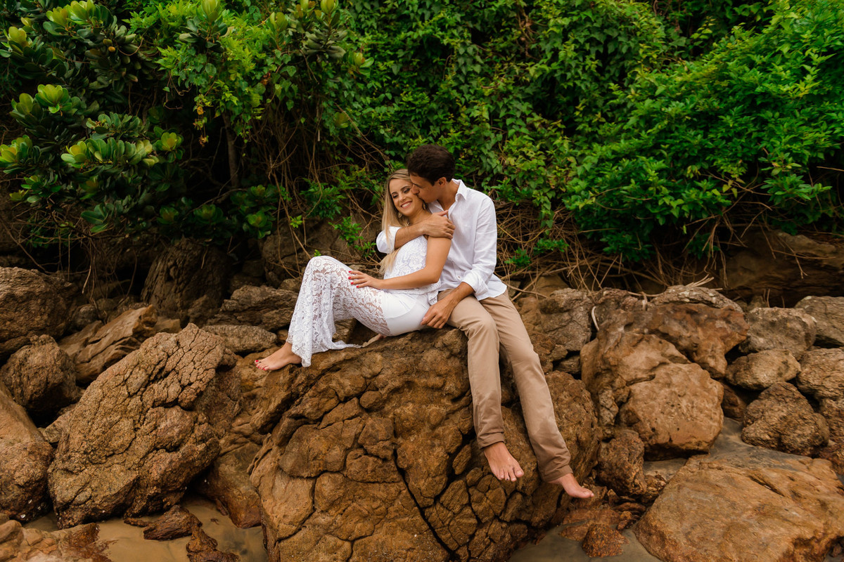 casal em rocha com o mar