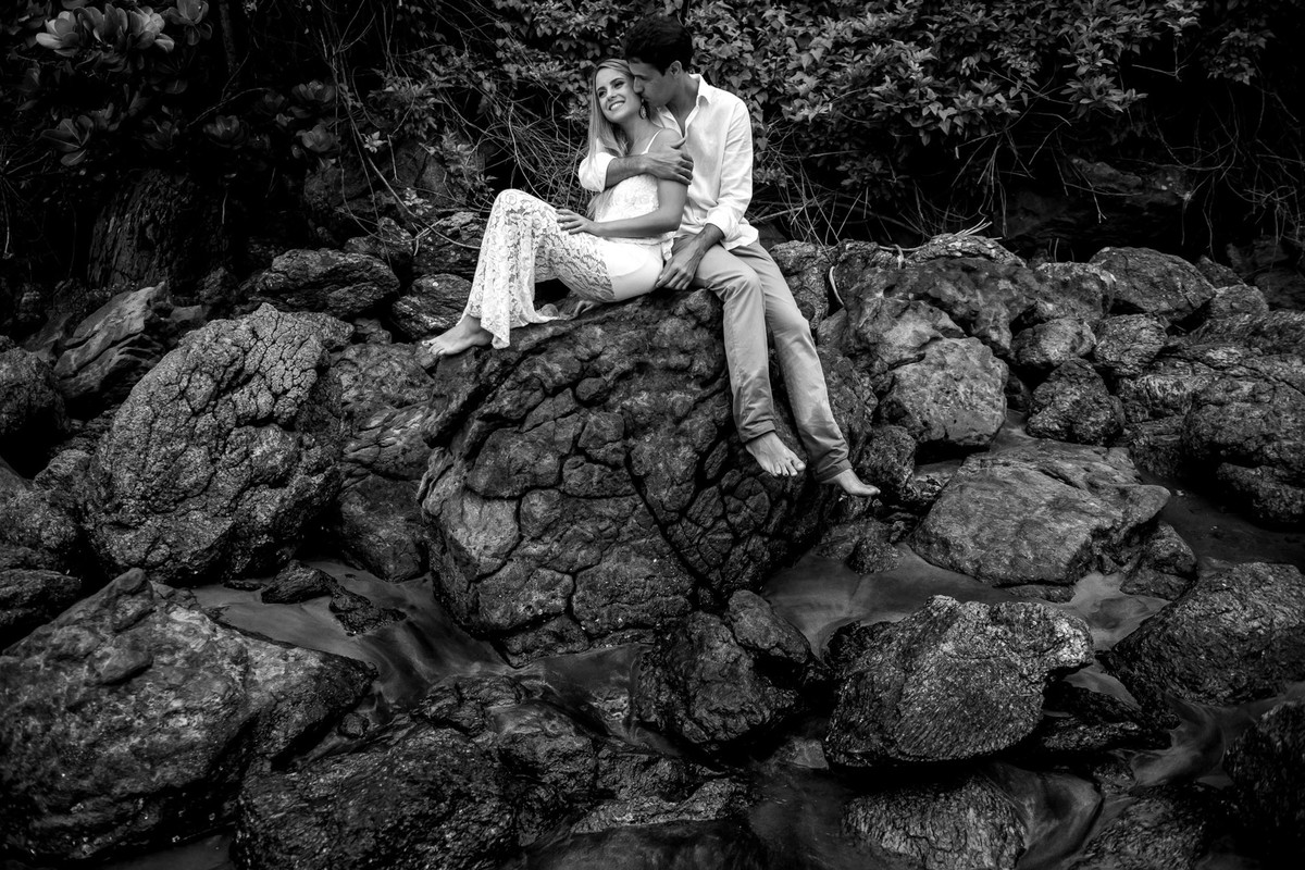 casal em rocha com o mar