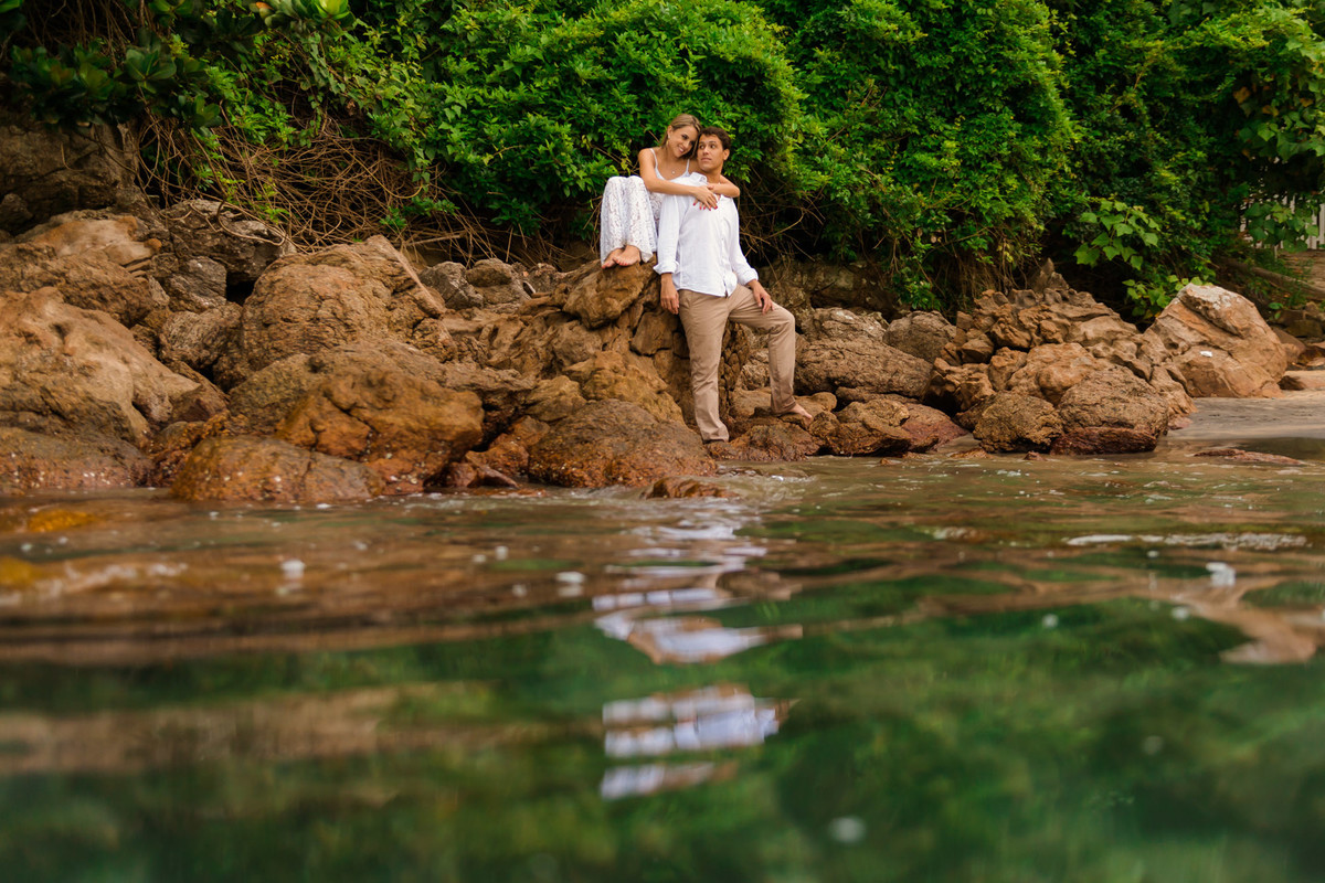 casal em rocha com o mar