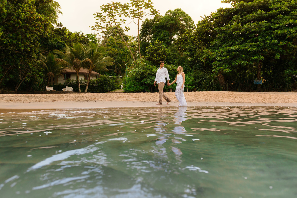 casal caminhando juntos de mãos na dadas na beira da praia