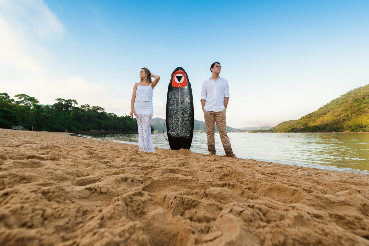 casal juntos com prancha de surf na praia